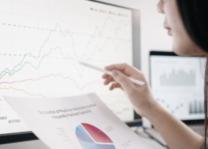 person comparing paper graph to data on computer screen