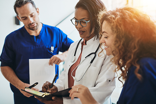 Doctors around clipboard (C) Adobe Stock. All rights reserved.