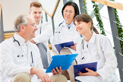 Four doctors talking and sitting on a staircase. (C) Adobe Stock. All rights reserved.