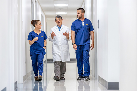 A UC Davis Health doctor and two healthcare workers walking down a hallway.