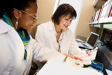 Two doctors sitting at a desk talking over some paperwork.