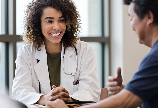 Female health care provider smiling talking to a male patient.