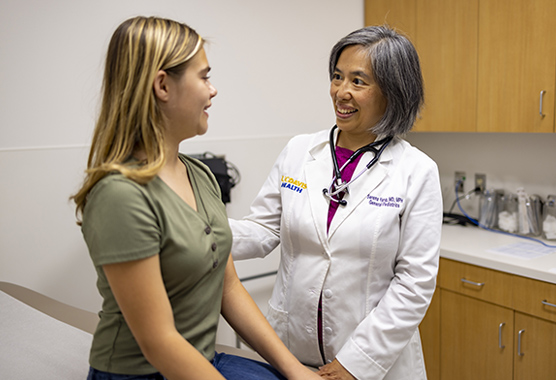 Adolescent girl talking with a female doctor in exam room.