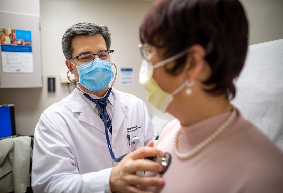 Male physician listening to the heart of a female patient with a stethoscope