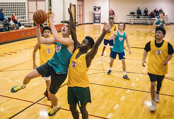 teenage boys playing basketball in a gym