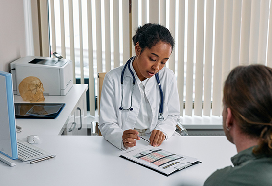 Health care provider talking to patient about demyelinating diseases while sitting at a desk.