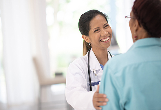 Female provider smiling a touching a patient’s shoulder.