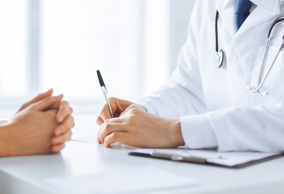 Close-up of the hands of a doctor in a white coat and a patient sitting at a table