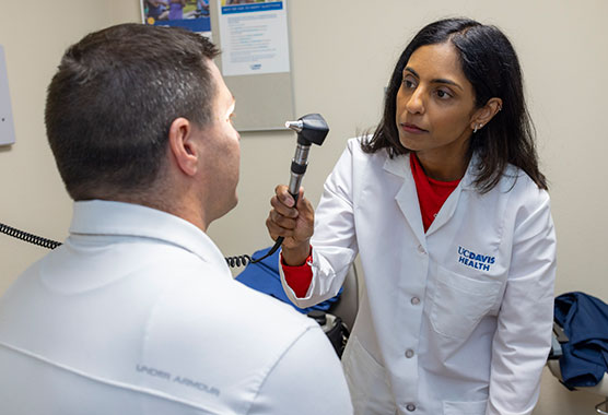 Female health care provider examining male patient’s eyes