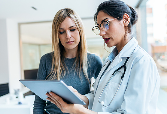 Female health care provider showing woman information on a mobile tablet.