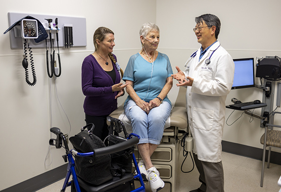 Older woman sitting on an exam table talking to her health care provider about hypothyroidism.