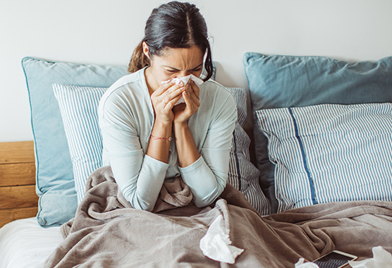 Woman blowing her nose in bed.