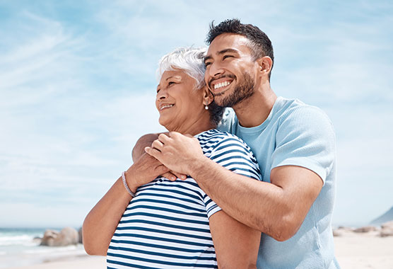 Younger man with his arm around his mother smiling outdoors