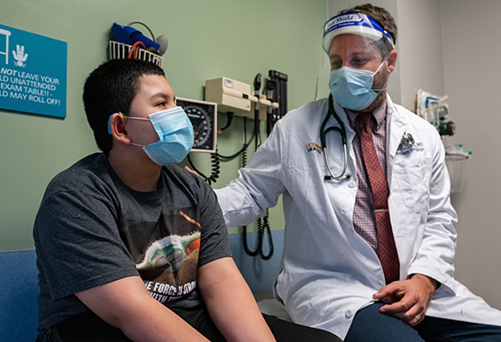 Boy sitting and talking to his physician in a doctor’s office.