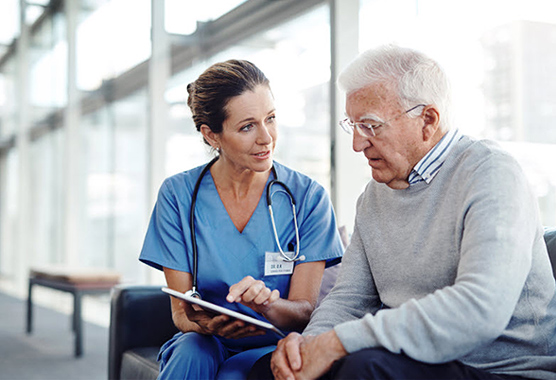 A female health care provider showing something to a mature male patient on a tablet  