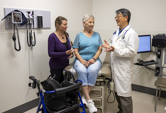 Woman and her caregiver in clinic talking to doctor about long qt syndrome.