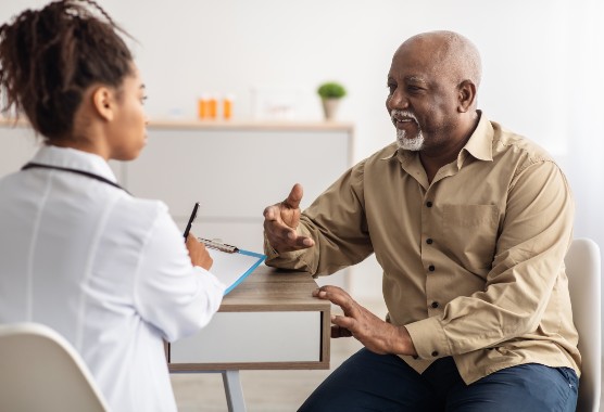 Female health care provider and male patient sitting at a desk talking