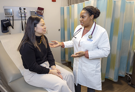 Female health care provider talking to female patient in exam room.