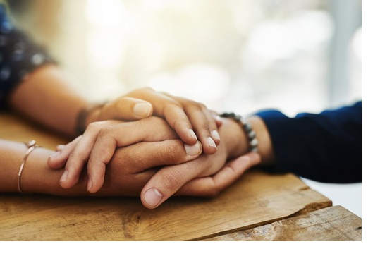 A person holding another person’s hand to comfort