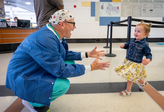 A young girl running to a provider in scrubs