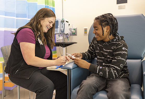 A child life specialist and pediatric patient laughing in the hospital