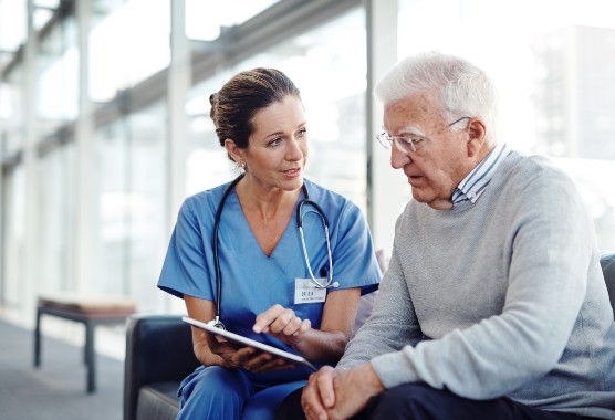 Female medical professional showing something to male patient on mobile tablet