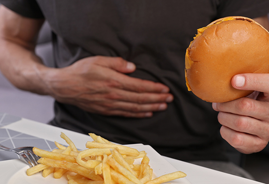 Man eating a burger and fries and getting sick.