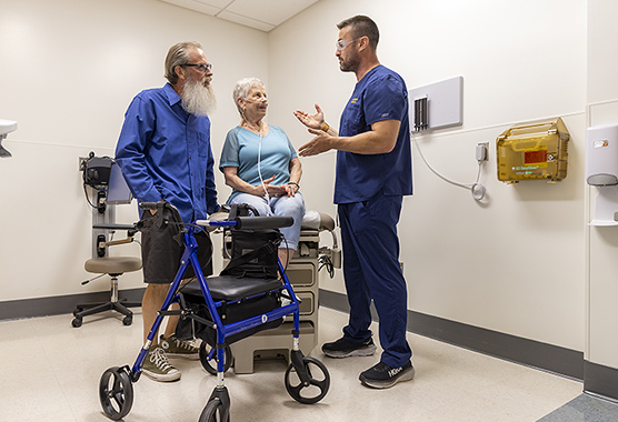 Older woman and man talking to a health care provider in a clinic room.