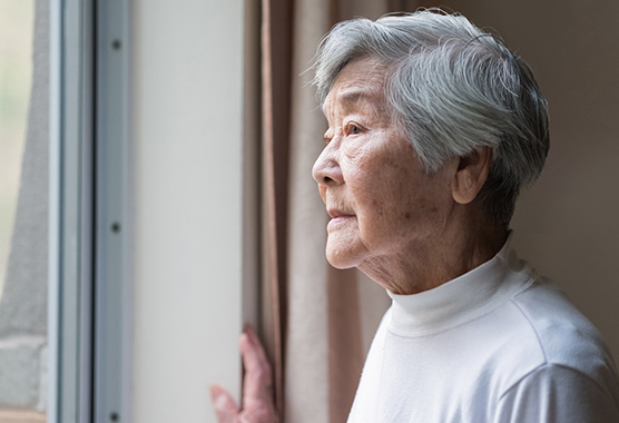 Older woman looking out the window.