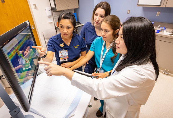 Group of healthcare workers pointing and looking at a screen in the hospital.