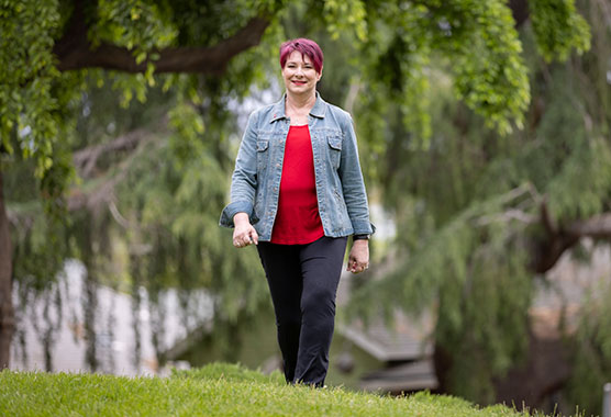 Woman walking across a grassy field with trees in the background