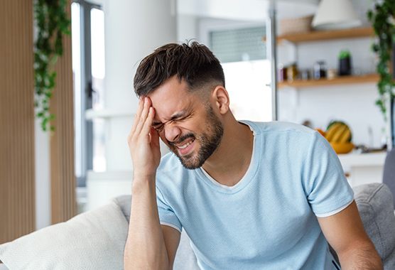 Man touching his head in pain from a TBI