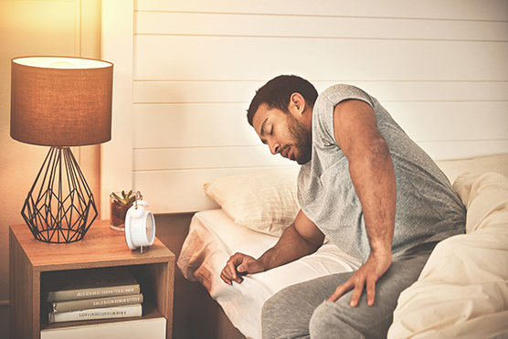 Man sitting up in bed in pain