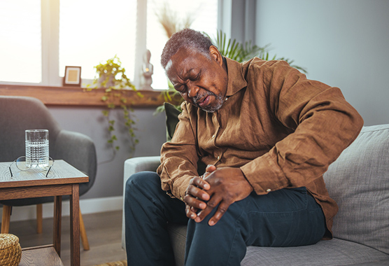 Older man holding his knee in pain.