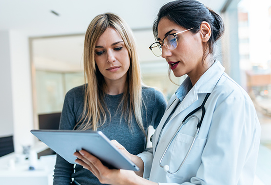 Female health care provider showing woman information on a mobile tablet.