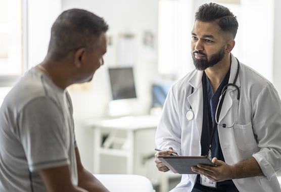 Male health care provider talking to male patient in a clinic.