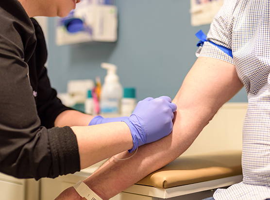 Individual getting blood drawn in exam room by health care worker