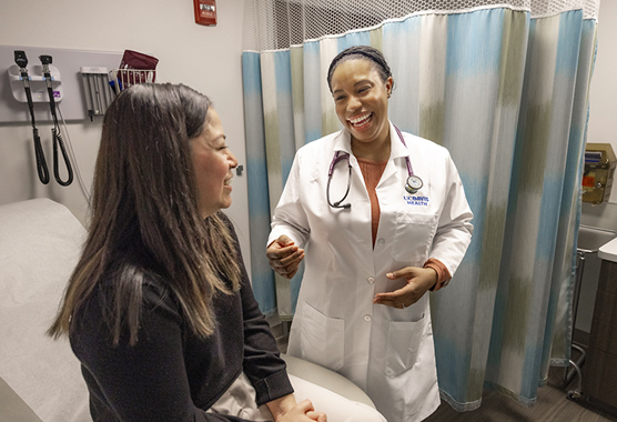 Female health care provider talking to female patient about women’s metabolic health in an exam room.