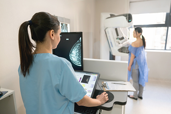 Woman getting mammogram while female health care provider looks on 