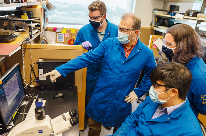 Four researchers looking at a computer screen in a lab.