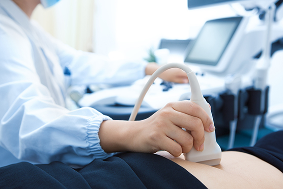 Closeup of an ultrasound exam being performed on an abdomen.