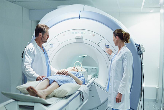 Male and female doctors preparing patient for MRI scan in hospital.
