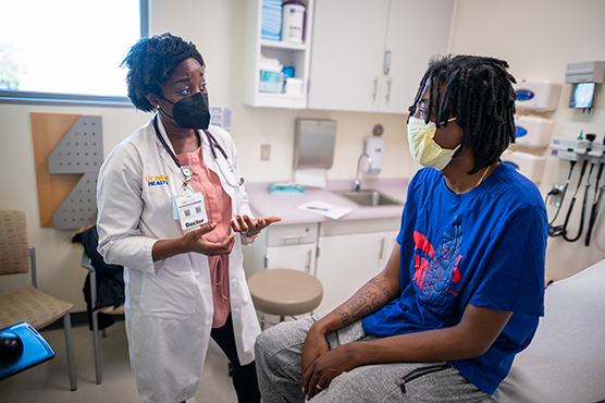 Younger male patient sitting on a clinic table talking to a health care provider.