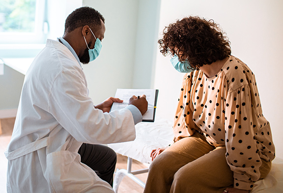 Health care provider showing female patient information on a clipboard.