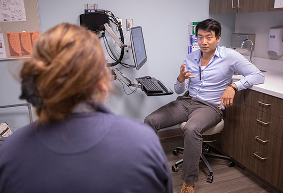 Male health care provider talking to female patient in a clinic room 