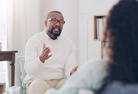 A man sitting and talking to another person.