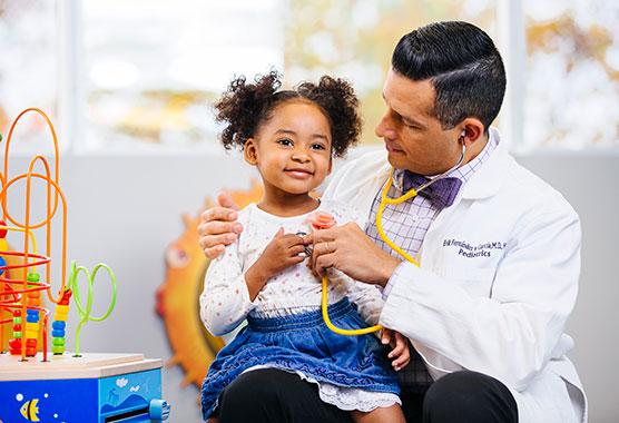 Male physician listening to young girl's heart with a stethescope