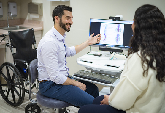 Rehab specialist discussing treatment with patient in front of a computer.