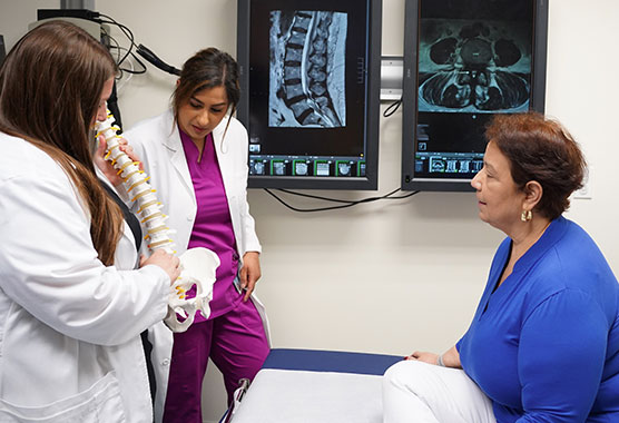 Spine specialist showing patient imaging of her spine in a clinic office