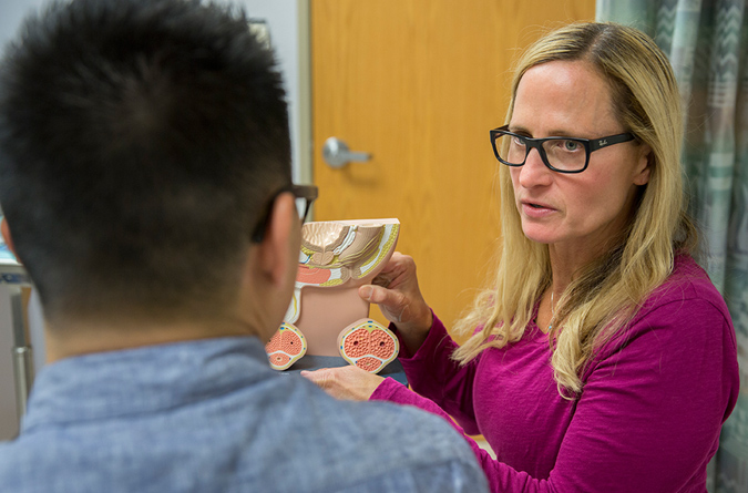 Female nurse practitioner talking to a male patient about urology conditions using a diagram.